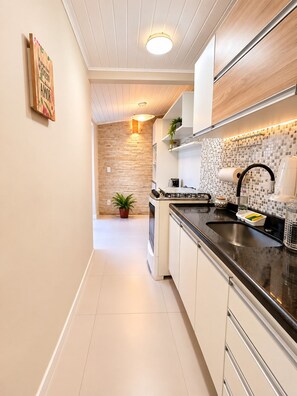 A modern kitchen with a black countertop, white cabinets, and a tiled backsplash.