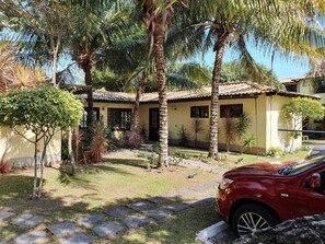 Ein Haus mit einem Ziegeldach, einer gepflasterten Auffahrt und einem roten Auto vor der Tür.