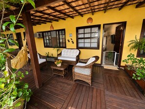 A covered outdoor seating area with wicker furniture, a hammock, and potted plants.