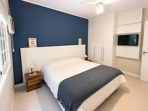 Ein Schlafzimmer mit Bett, Nachttisch, Fernseher und Kleiderschrank.