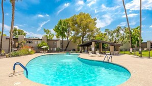 Une piscine avec une terrasse bleue, des chaises longues et un espace salon abrité.