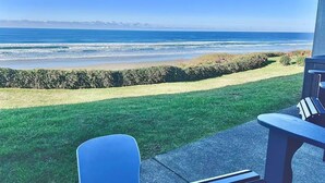 Un patio con vista al océano, un área con césped y una zona de estar con mesa y sillas.