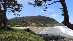 Un paisaje costero con playa, costa rocosa y colinas boscosas.