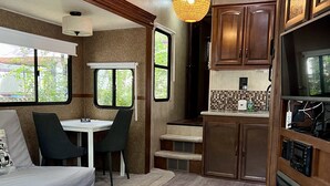 Ein kompaktes Wohnmobil-Interieur mit einer Küchenzeile, Essbereich und einer kleinen Sitzecke.