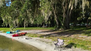 Ein Strand mit Kajaks, einem Stuhl und einem Picknicktisch.