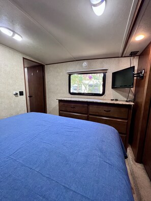 Ein Schlafzimmer mit einem Bett, einem Fenster mit Blick, einem Fernseher und einer Tür.