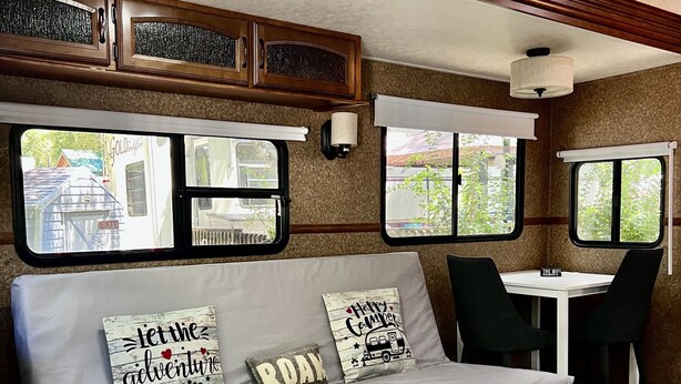 Ein gemütliches Wohnmobil-Interieur mit Sofa, Hocker und Essbereich.