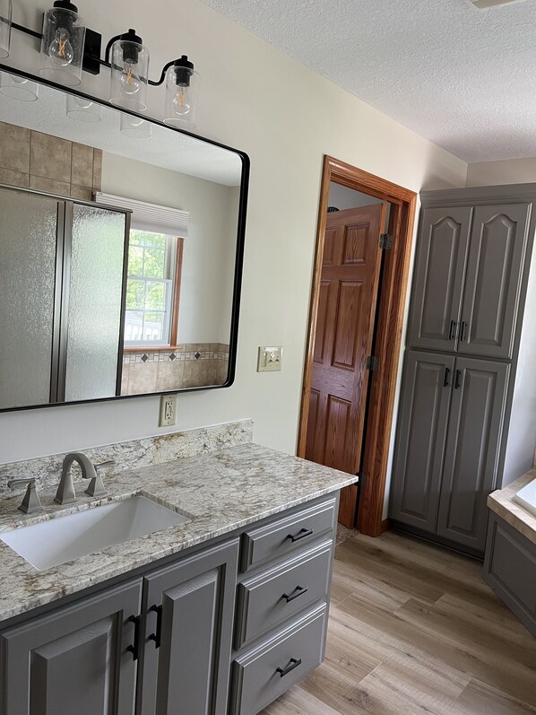 Une salle de bain avec un grand miroir, un lavabo et un meuble de rangement.