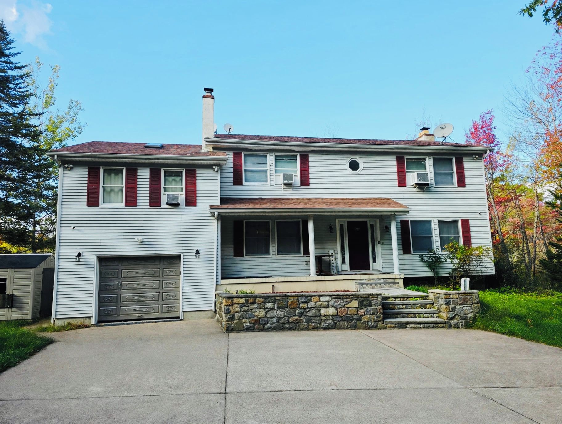 A two-story house with a garage, a covered porch, and a stone foundation.