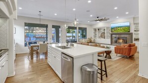 Une cuisine moderne dotée d’un îlot central, d’un coin repas et d’un salon avec une cheminée.