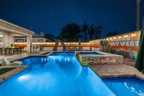 Une piscine agrémentée d’une fresque murale et d’éclairages, entourée d’une terrasse.