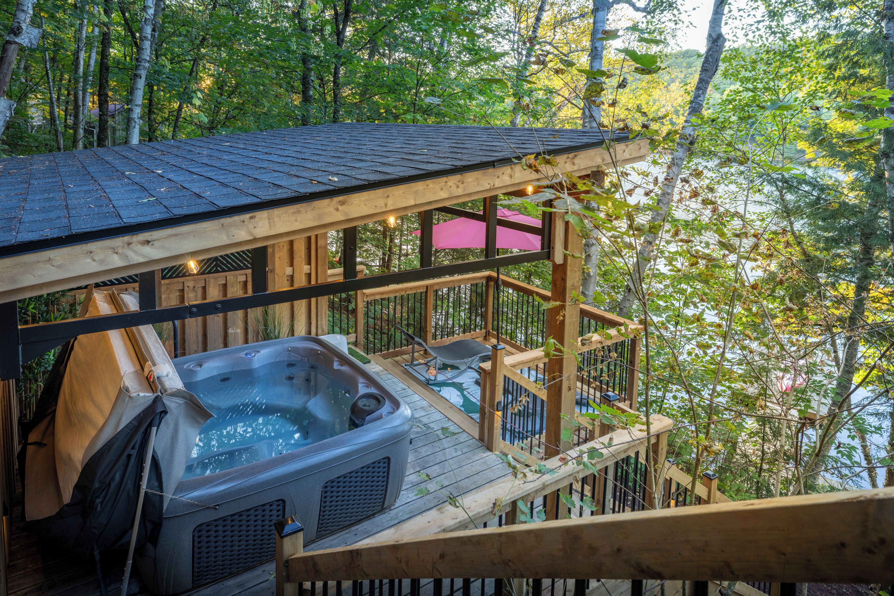 A hot tub on a wooden deck with a view of a forest.