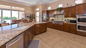 A spacious kitchen with granite countertops, stainless steel appliances, and wooden cabinets.