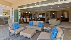 An open-plan living area with a dining table, multiple sofas, and a kitchen in the background.