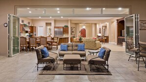 A spacious living area with a sofa set, a dining table, and a kitchen in the background.