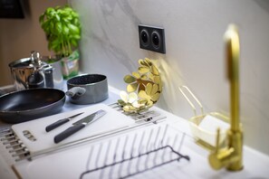 Una encimera de cocina con una sartén, una olla, un cuchillo, un cuaderno y un par de gafas.