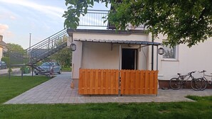 Un petit bâtiment entouré d’une clôture en bois, avec un escalier et des vélos garés à l’extérieur.
