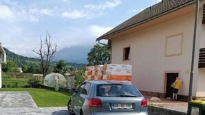 Une voiture est garée sur une allée pavée, avec une maison en arrière-plan.