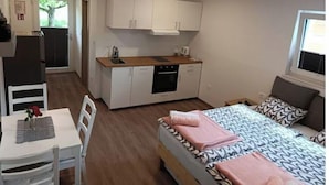 Une chambre à coucher de taille modeste, comprenant un lit, des tables de chevet et une fenêtre.