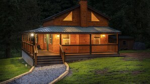Een houten hut met een veranda, schoorsteen en een metalen dak.