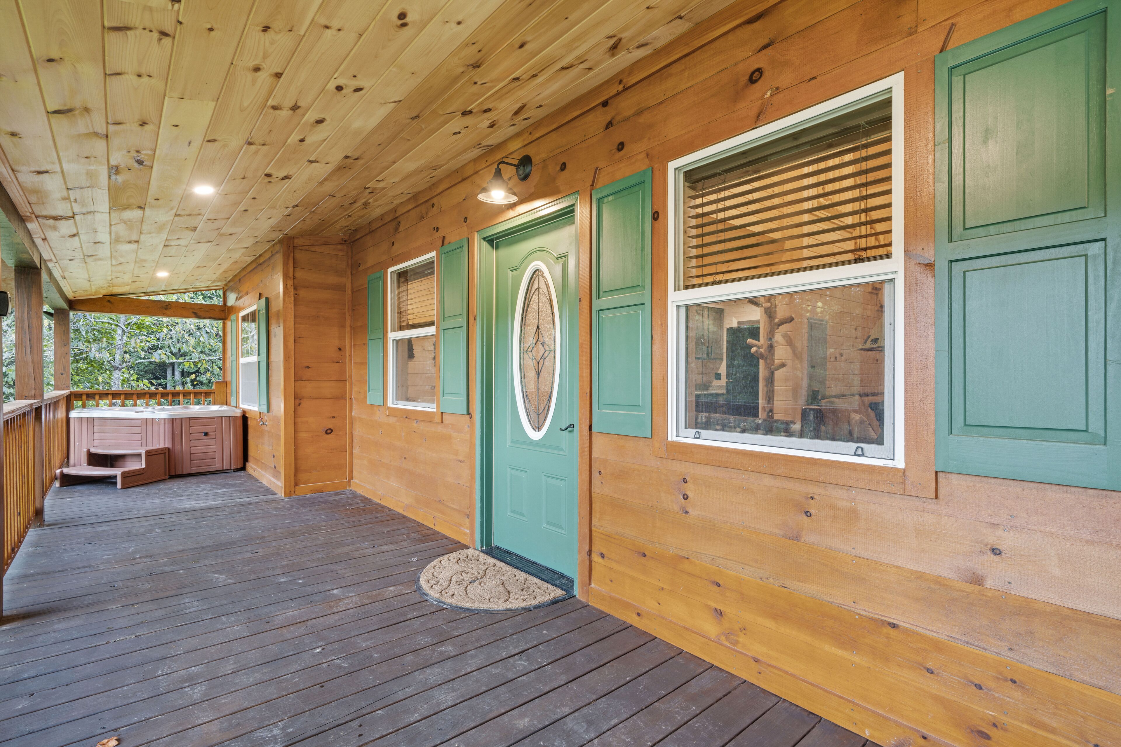 A wooden cabin with a porch, a green door, and a small outdoor seating area.