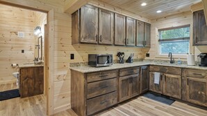 Een houten keukentje in cottage-stijl met inbouwkastjes, een magnetron en een raam.