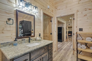 Bathroom features a granite countertop, large mirror, and a washing machine.