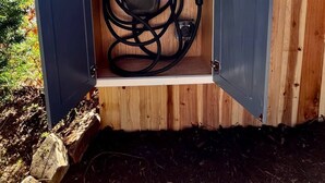 A wooden structure with a roof, containing a generator and a power cord.
