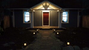 A house with a dark entrance, a red door, and two windows on either side.