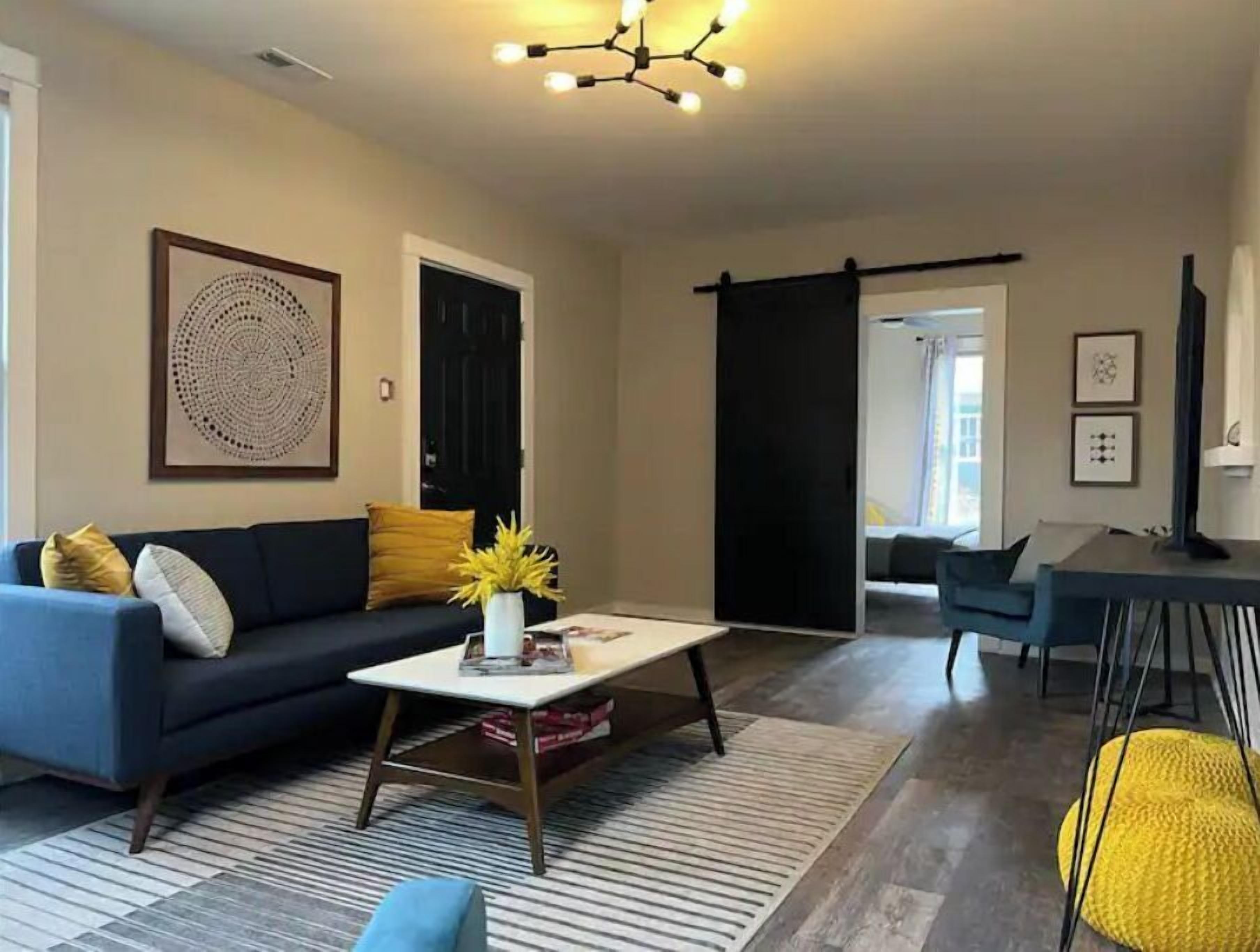 Een moderne woonkamer met een bank, salontafel en een schuifdeur naar een andere kamer.