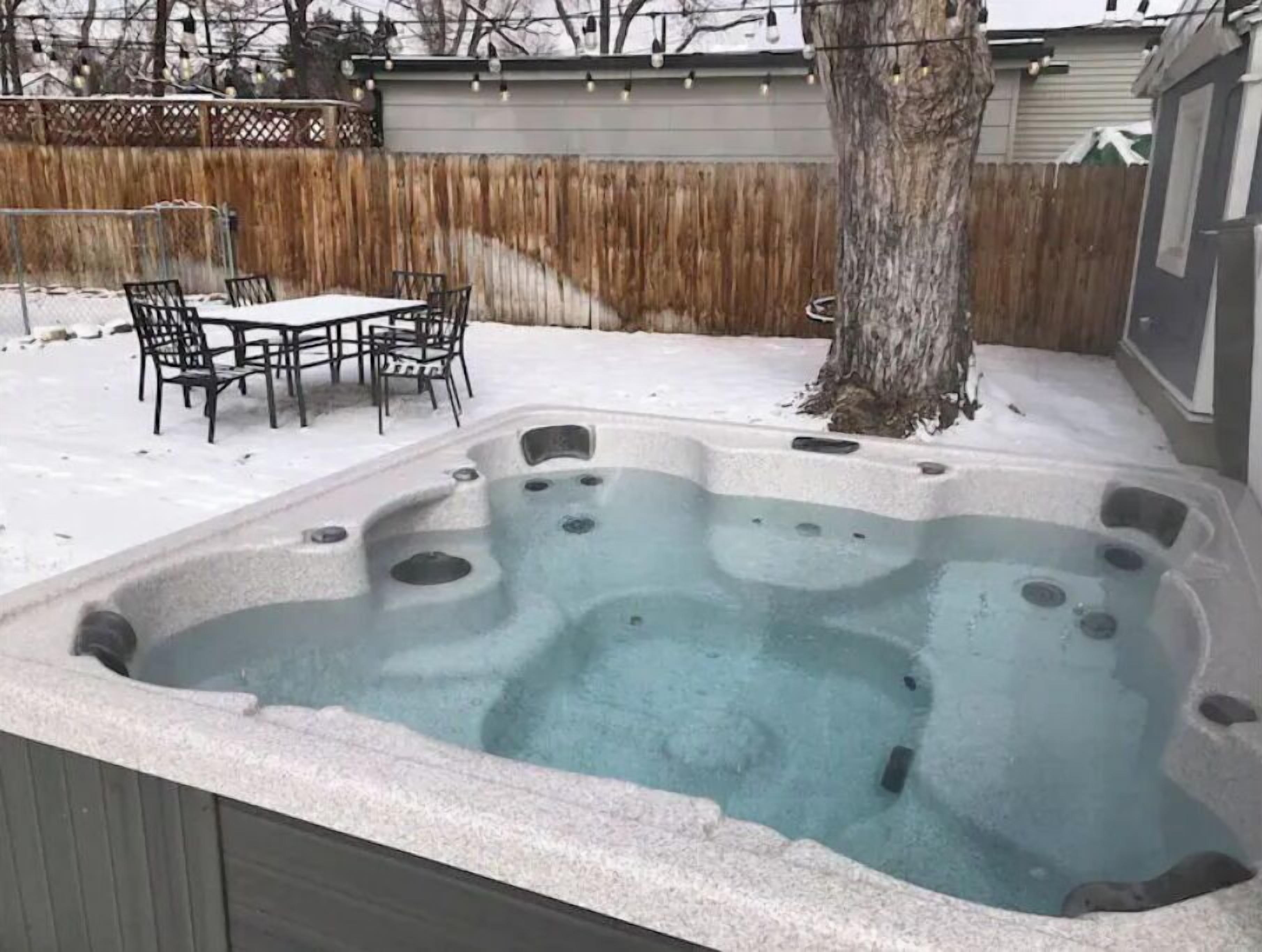 Un bain à remous avec une terrasse en bois et des chaises.