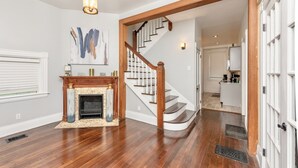 A spacious living room with hardwood flooring, a fireplace, and a staircase leading to another level.