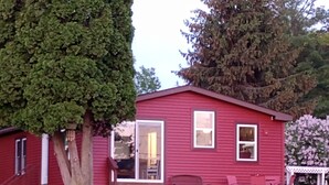 Una casa vermella amb un porxo i un arbre al davant.