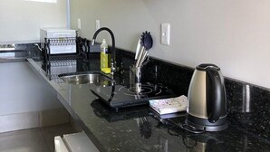 Een keuken met een zwart aanrecht, een roestvrijstalen waterkoker en een broodrooster.