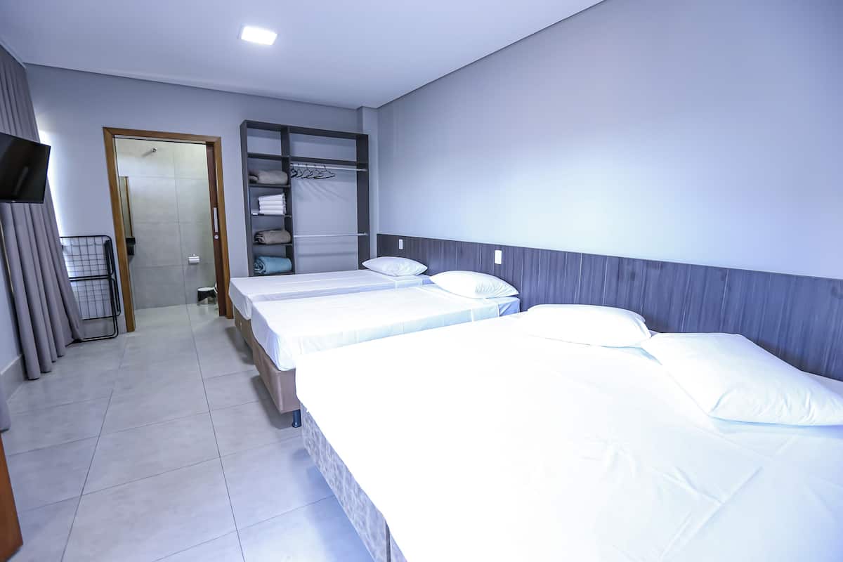 A hotel room with two beds, a walk-in closet, and a television on the wall.