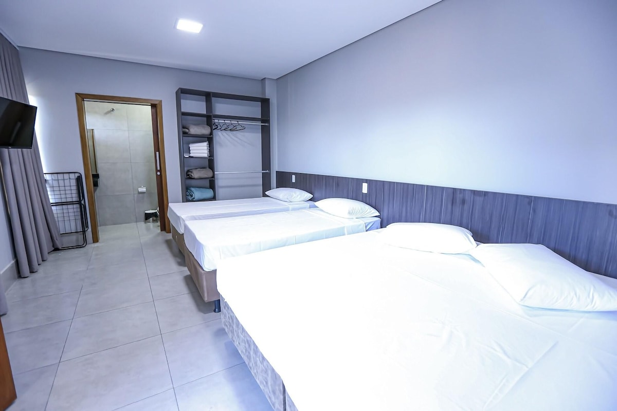 Una habitación de hotel con dos camas, un armario, televisión y zona de ducha.