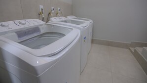 A laundry room with three front-loading washing machines and a dryer. - Vila Nóbrega Residencial (Foz do Iguaçu)