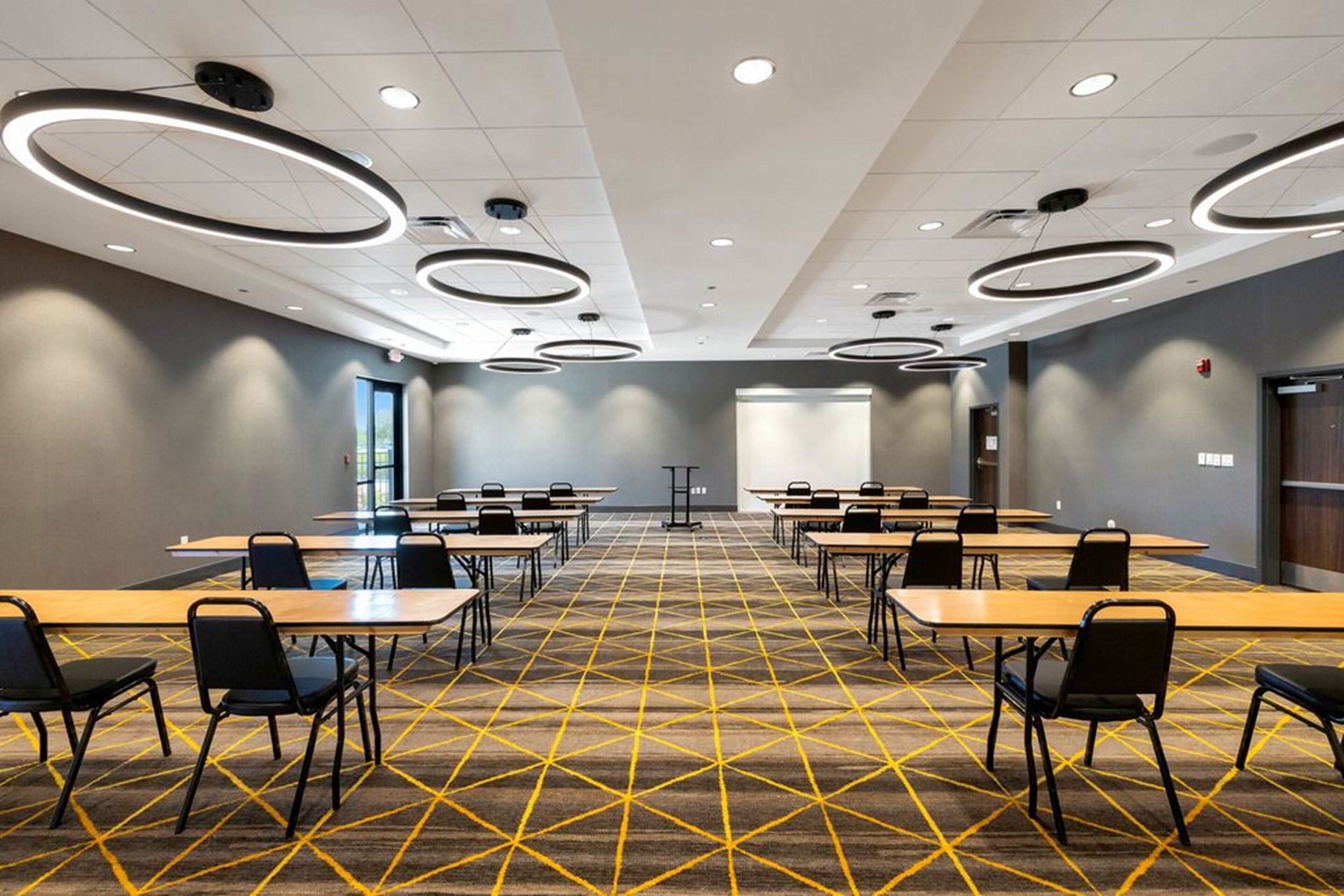 A conference room with a geometric carpet pattern, round ceiling lights, and a neutral color scheme.