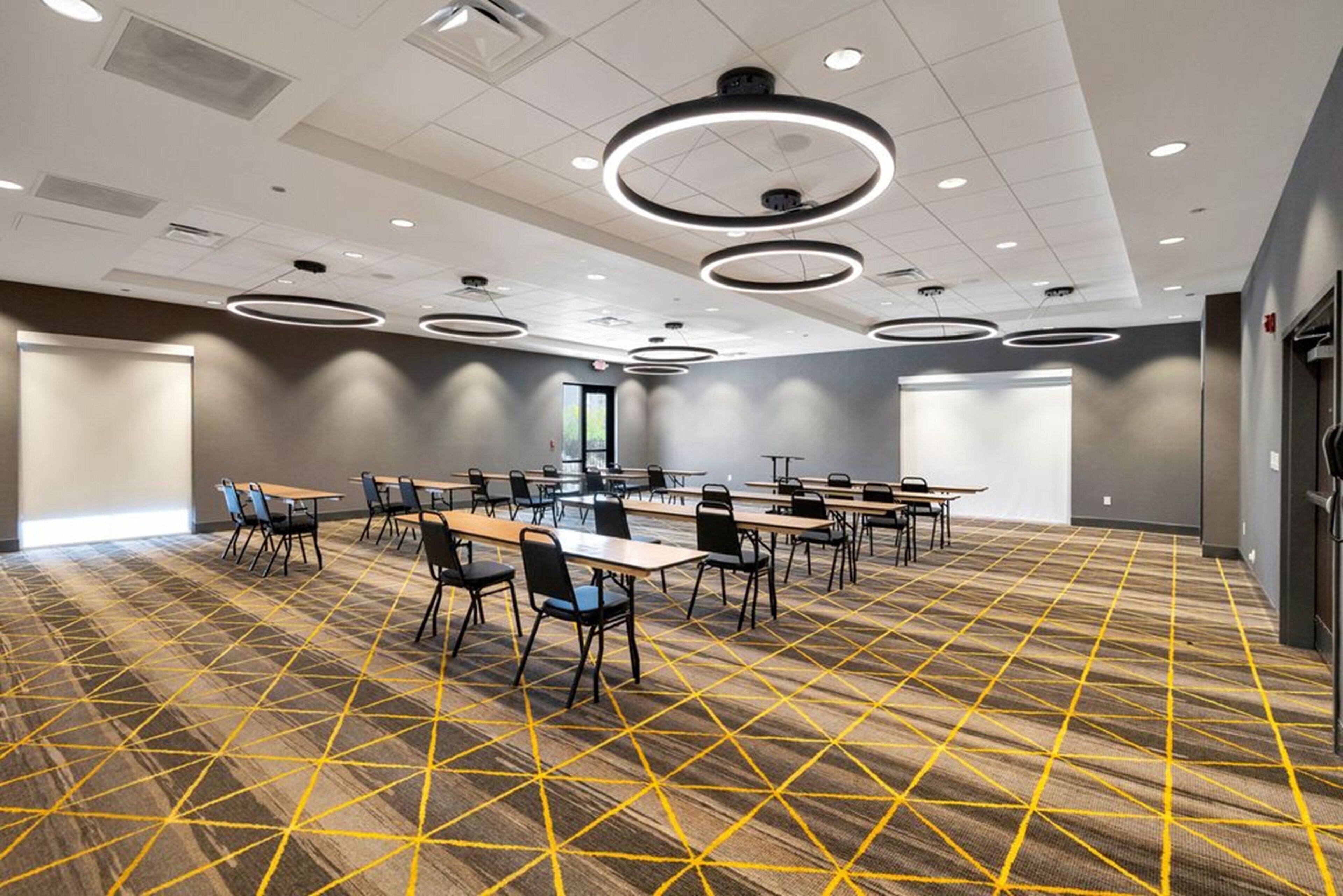 A conference room with tables and chairs, a patterned carpet, and circular ceiling lights.