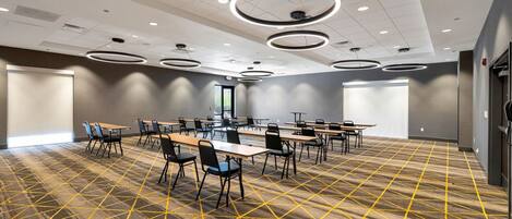A conference room with tables and chairs, a patterned carpet, and circular ceiling lights.