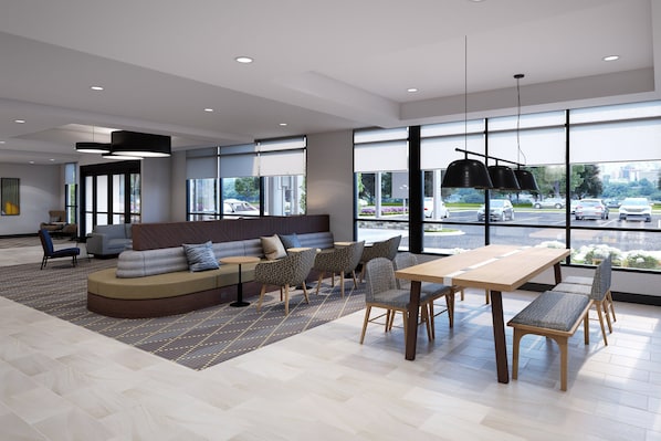 A modern interior with a large seating area, a wooden table, and large windows offering a view of the parking lot.