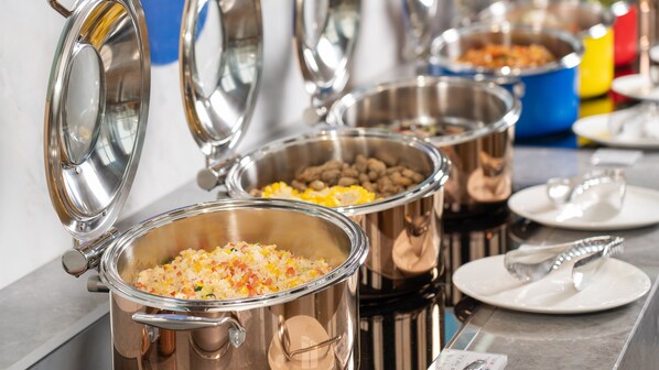 Un buffet proposant une variété de plats présentés dans des récipients en acier inoxydable.