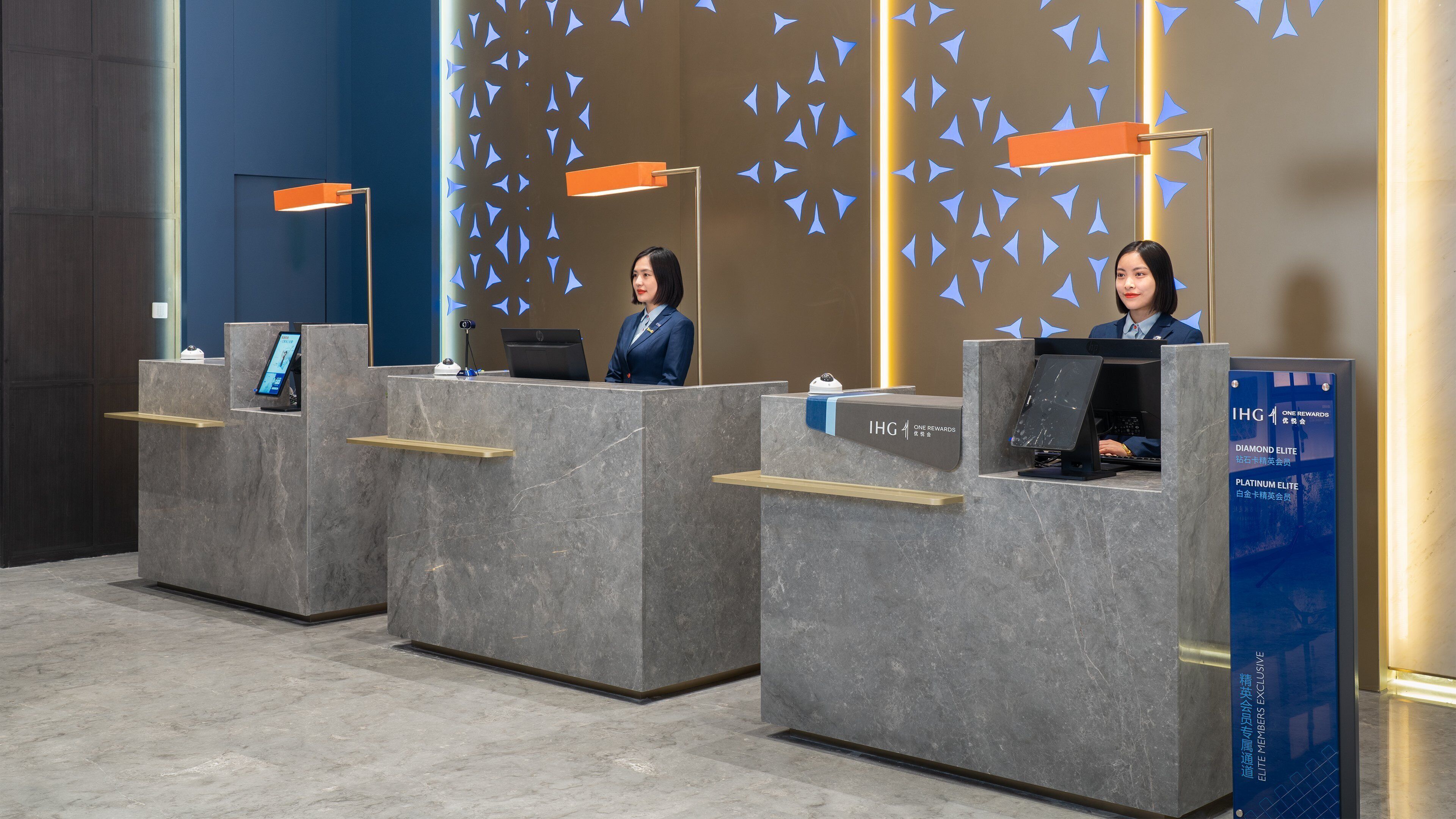 A reception area with three counters, each equipped with a computer and a small shelf.