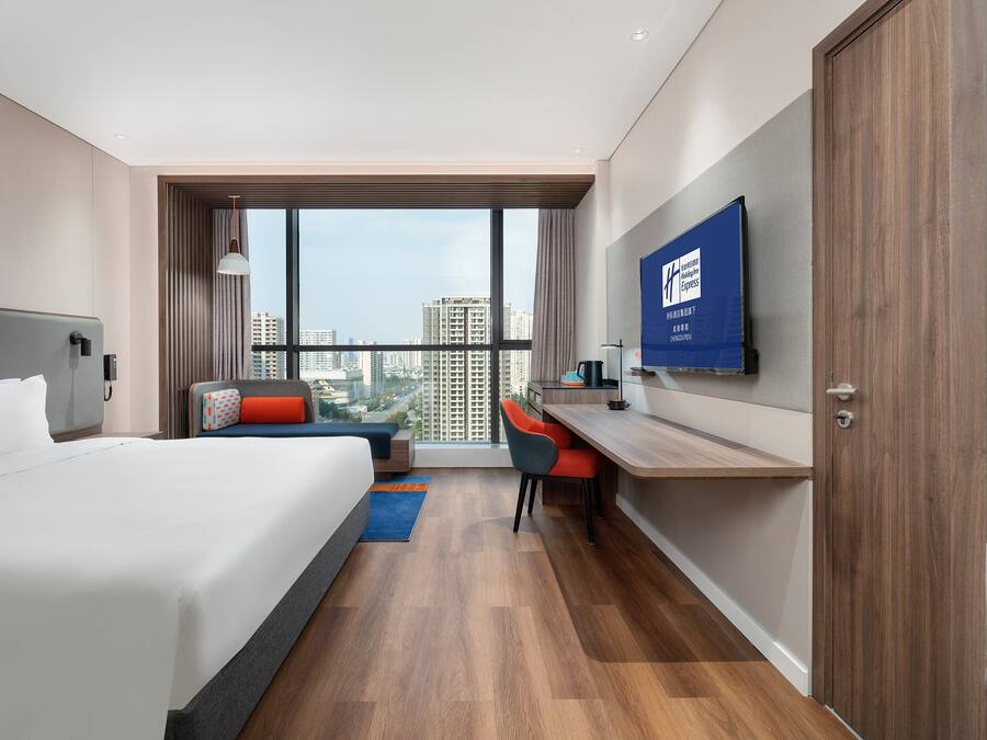 Een moderne hotelkamer met een groot bed, een bureau en een televisie.