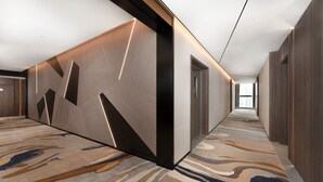 A modern hotel corridor with a geometric patterned wall, a carpeted floor, and a view to the outside. - Holiday Inn Express Chengdu Pidu by IHG (Chengdu)