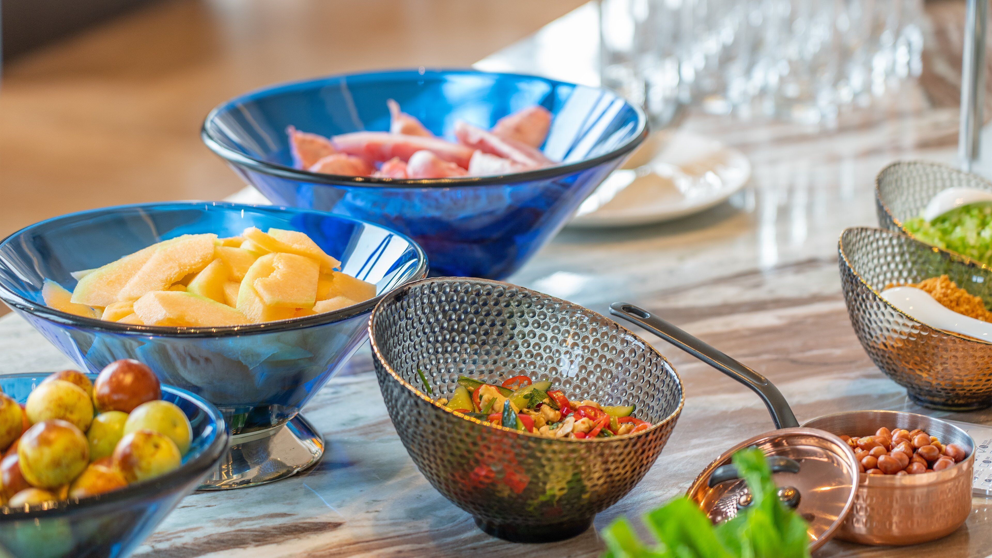 Una mesa con varios recipientes que contienen frutas y verduras.