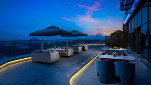 A rooftop bar with outdoor seating, umbrellas, and a city view at dusk. - Holiday Inn Express Chengdu Pidu by IHG (Chengdu)