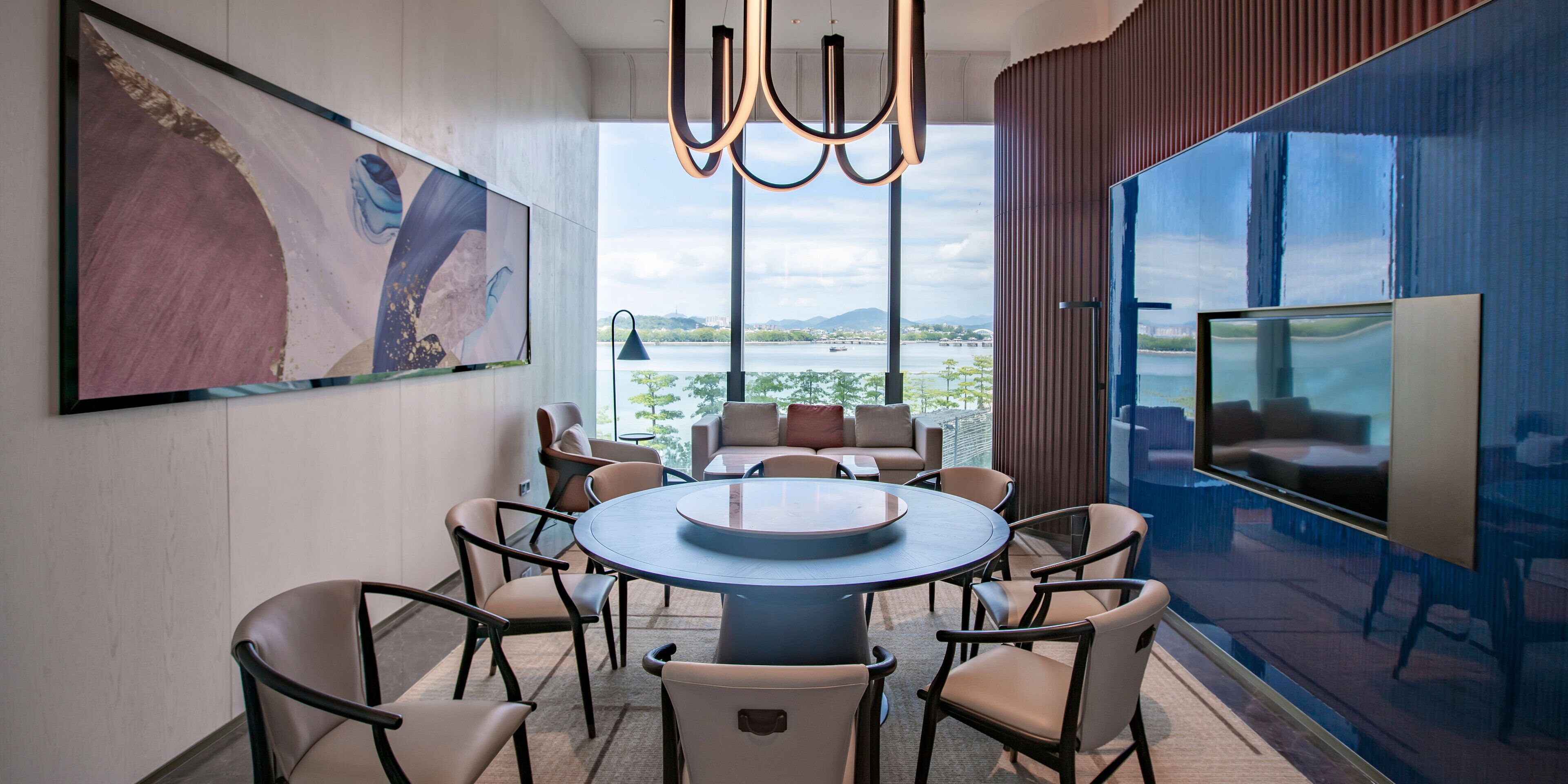 Un espace repas moderne avec une table ronde, des chaises et un grand tableau accroché au mur.