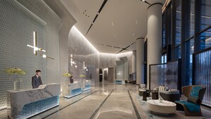Un hall d’entrée moderne doté d’un comptoir d’accueil, d’un espace salon et de grandes fenêtres.
