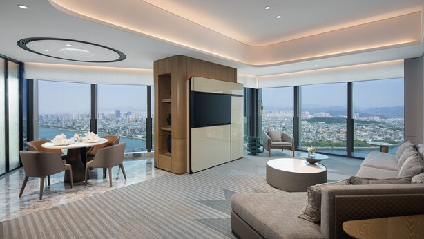 Un salon moderne comprenant un coin repas, de grandes fenêtres offrant une vue sur la ville et un espace salon confortable.